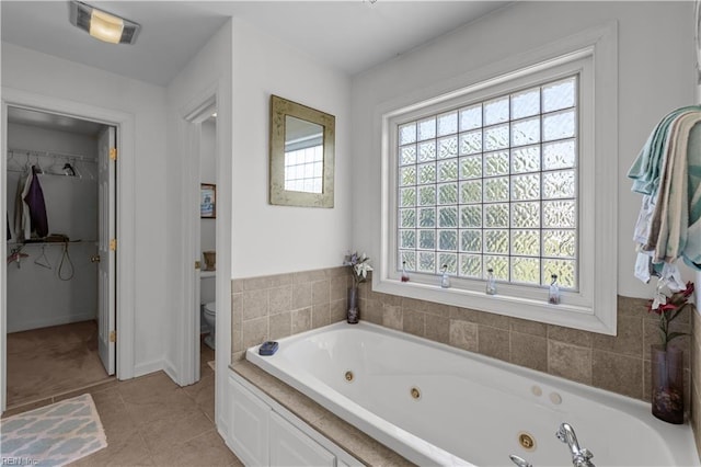 bathroom with a walk in closet, visible vents, a tub with jets, tile patterned floors, and toilet