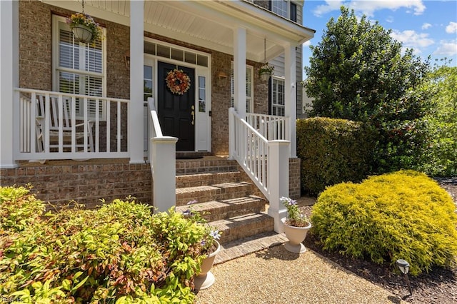 doorway to property with brick siding and covered porch