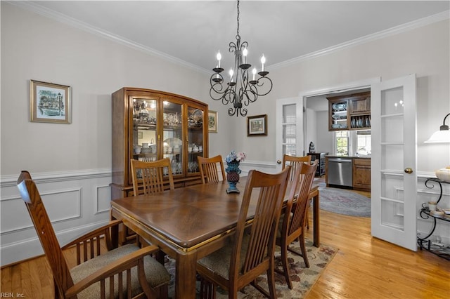 dining space featuring ornamental molding, light wood finished floors, and a notable chandelier