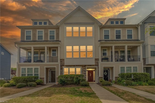 townhome / multi-family property featuring a standing seam roof, metal roof, and stone siding