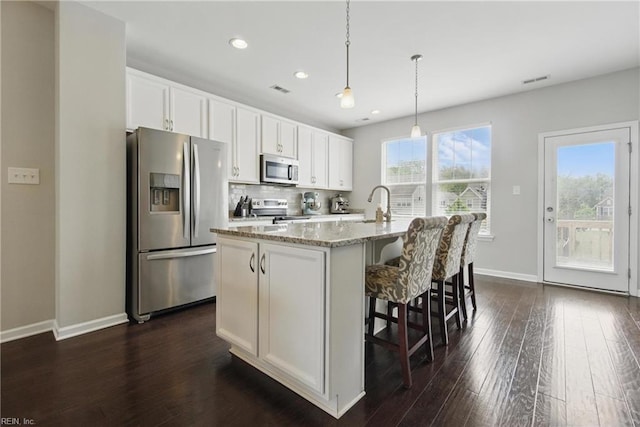 kitchen with white cabinets, recessed lighting, appliances with stainless steel finishes, and a center island with sink