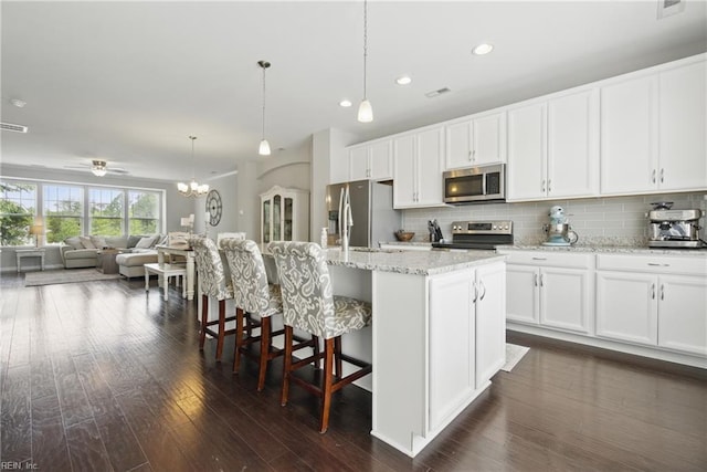 kitchen featuring white cabinets, stainless steel appliances, dark wood finished floors, and decorative backsplash