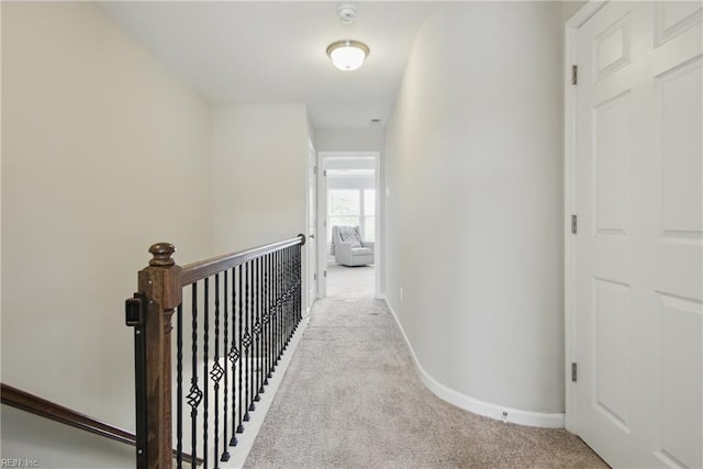 hall featuring baseboards, carpet flooring, and an upstairs landing