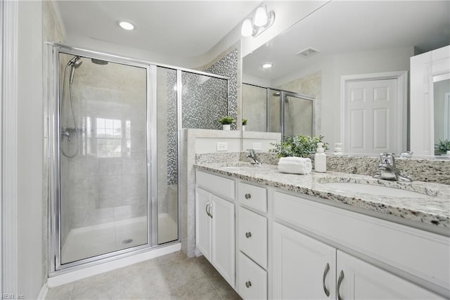 full bath with double vanity, a sink, tile patterned floors, and a shower stall