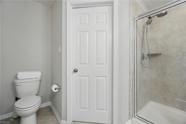 bathroom featuring baseboards, tile patterned floors, a stall shower, and toilet
