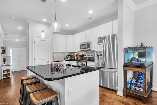 kitchen featuring crown molding, dark countertops, hardwood / wood-style flooring, a sink, and appliances with stainless steel finishes