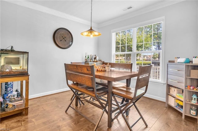 dining space featuring baseboards, visible vents, ornamental molding, and light wood finished floors