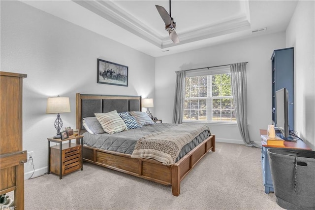 bedroom featuring light carpet, baseboards, a tray ceiling, visible vents, and ornamental molding