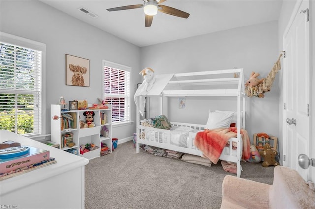 carpeted bedroom with ceiling fan, visible vents, multiple windows, and baseboards