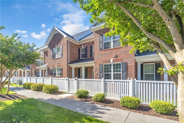 view of front of property with brick siding, a fenced front yard, and a gate