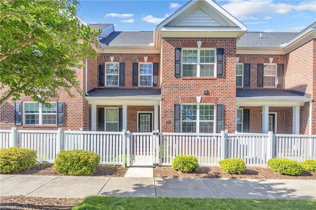 multi unit property featuring brick siding, a fenced front yard, and a gate