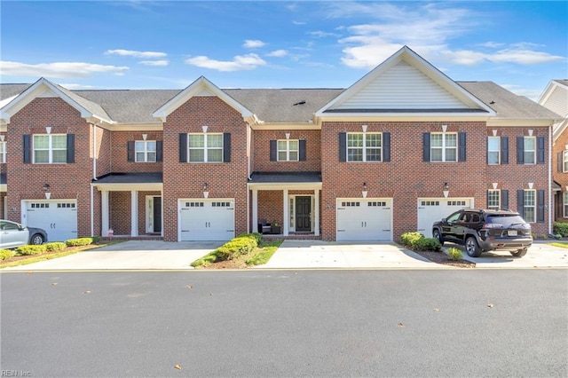 view of property featuring brick siding, a garage, and driveway