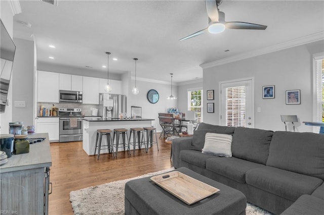 living area with crown molding, recessed lighting, ceiling fan, and wood finished floors