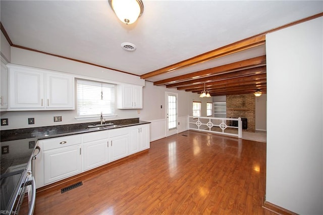 kitchen with visible vents, dark countertops, wood finished floors, a sink, and white cabinetry