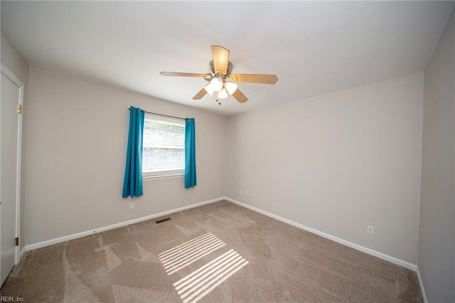 carpeted spare room with baseboards, visible vents, and ceiling fan