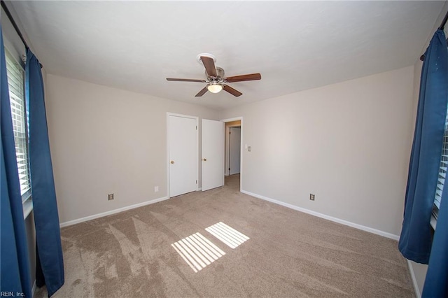 unfurnished bedroom with baseboards, light colored carpet, and ceiling fan
