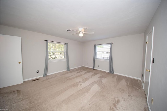 spare room featuring a ceiling fan, baseboards, visible vents, and light carpet