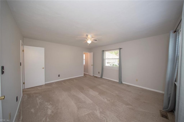 empty room featuring baseboards, a ceiling fan, and light colored carpet