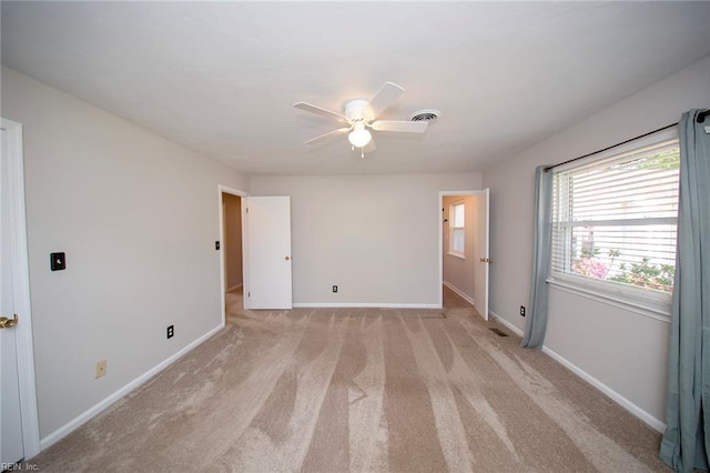 spare room with a ceiling fan, baseboards, visible vents, and light colored carpet