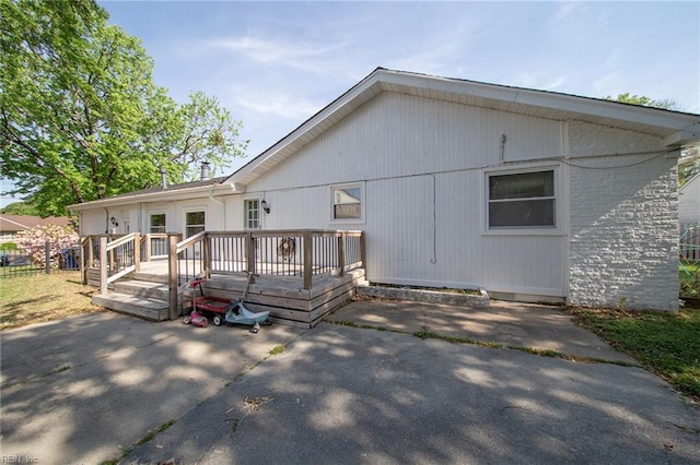 rear view of house with a wooden deck and a patio area