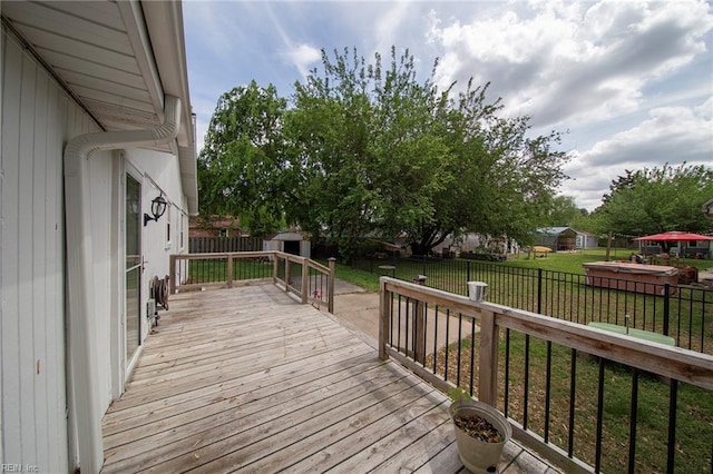 deck featuring a storage shed, a lawn, an outbuilding, and a fenced backyard