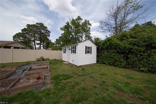 view of yard featuring a storage shed, a garden, fence, and an outbuilding