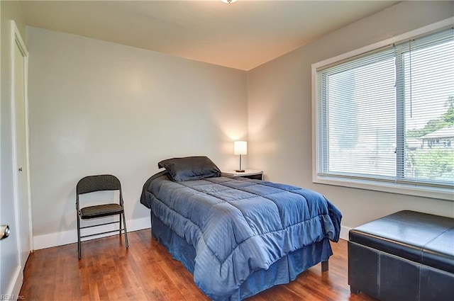 bedroom featuring baseboards, wood finished floors, and multiple windows