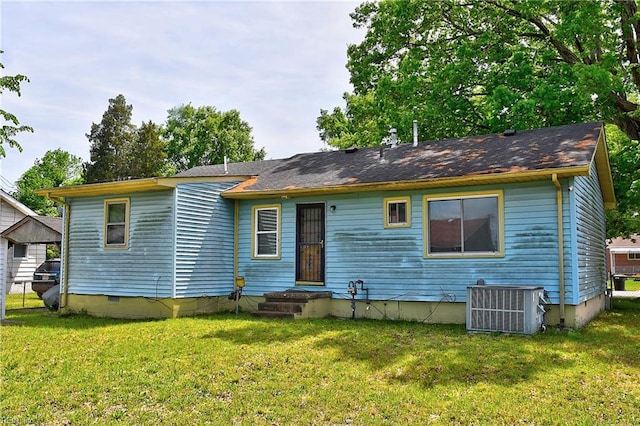 rear view of property with central AC unit, a yard, and crawl space