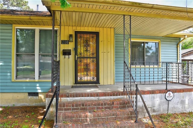 entrance to property featuring a porch and crawl space