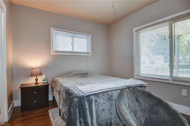 bedroom with dark wood-style flooring, baseboards, and multiple windows