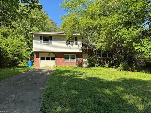 tri-level home with a garage, driveway, brick siding, and a front yard