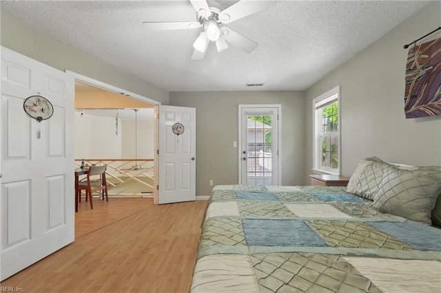 bedroom with a ceiling fan, light wood finished floors, a textured ceiling, and access to exterior