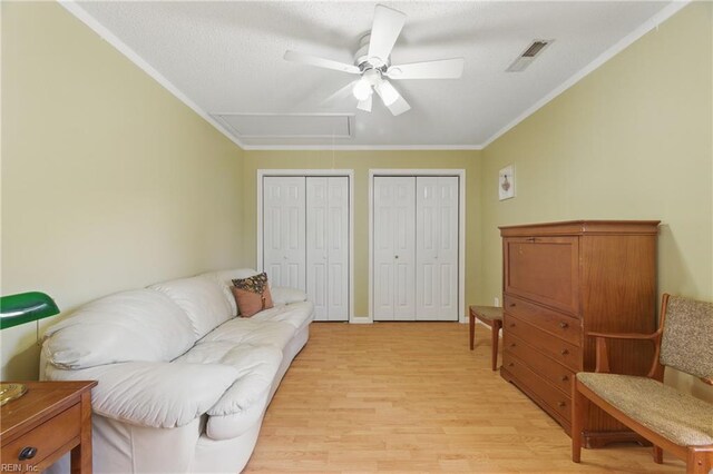 sitting room featuring crown molding, light wood finished floors, attic access, a ceiling fan, and visible vents
