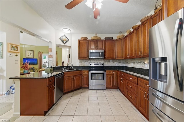 kitchen with appliances with stainless steel finishes, a sink, a ceiling fan, light tile patterned floors, and tasteful backsplash