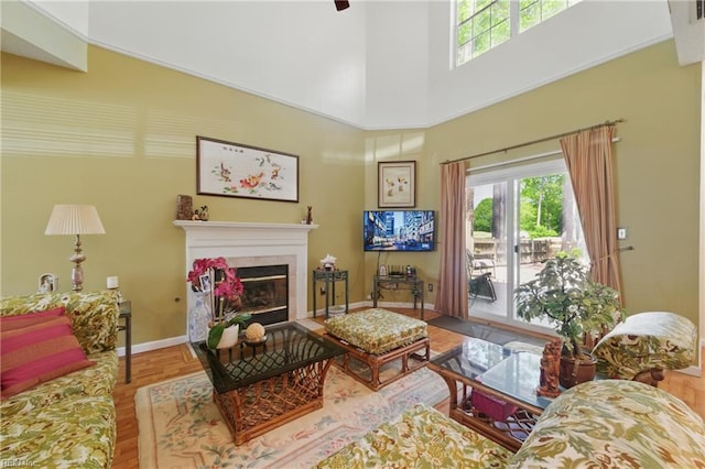 living area with baseboards, wood finished floors, a healthy amount of sunlight, and a tile fireplace