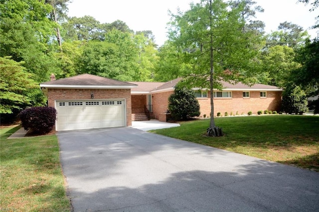 ranch-style home with a chimney, a front yard, brick siding, concrete driveway, and an attached garage