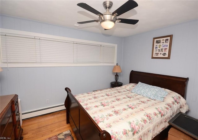 bedroom with a ceiling fan, wood finished floors, and baseboard heating