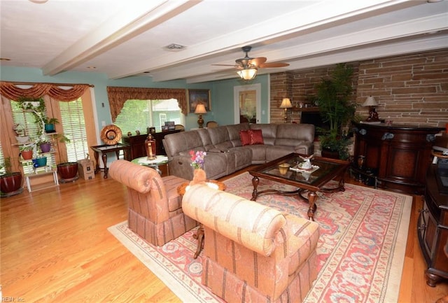 living area featuring visible vents, a ceiling fan, wood finished floors, and beamed ceiling