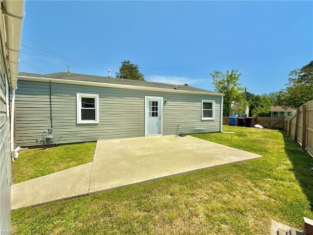 rear view of house with a fenced backyard, a yard, and a patio area