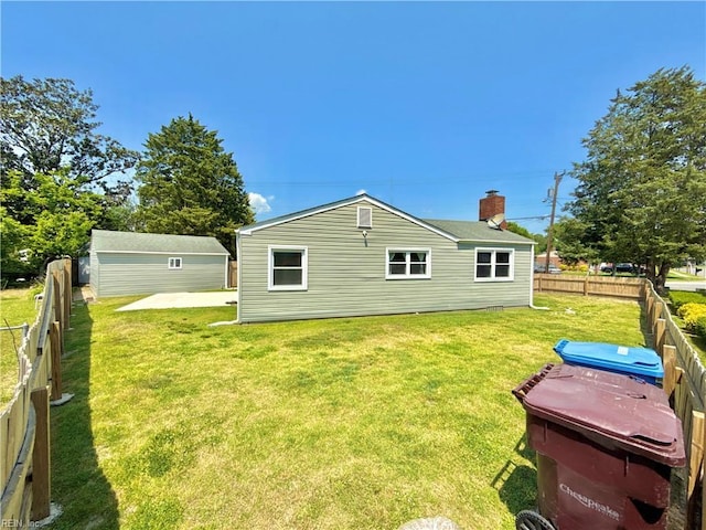 rear view of house with a lawn, an outdoor structure, and a fenced backyard