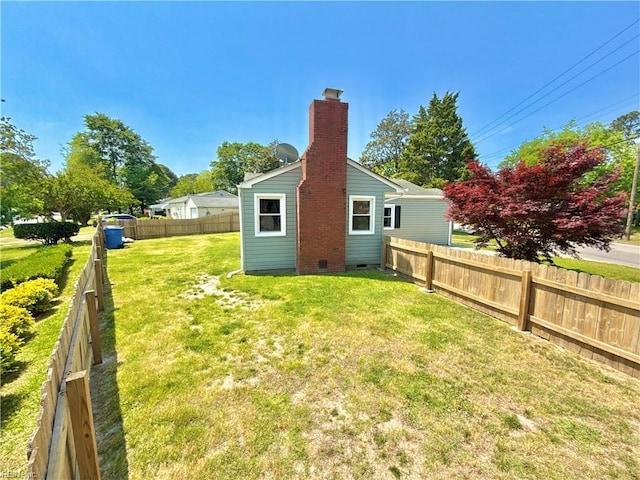 rear view of house featuring a fenced backyard, crawl space, a yard, and a chimney