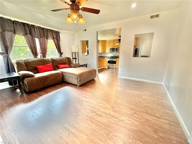 living area featuring visible vents, a ceiling fan, light wood-style flooring, and baseboards