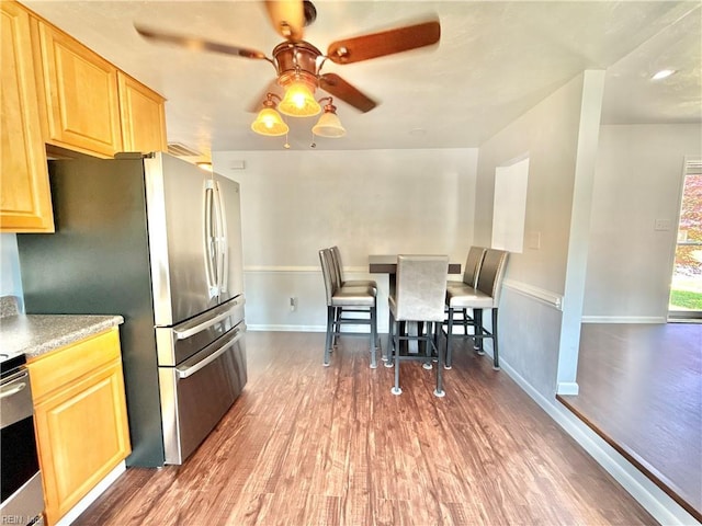 kitchen featuring a ceiling fan, baseboards, wood finished floors, and light brown cabinets