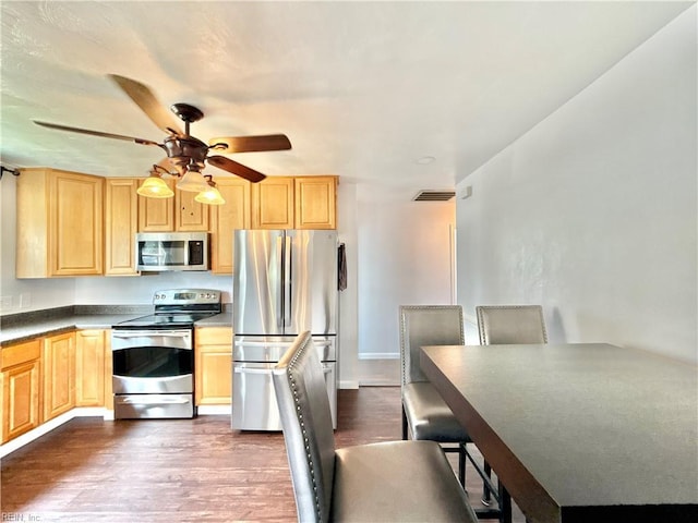 kitchen featuring stainless steel appliances, visible vents, dark wood-style floors, and light brown cabinets