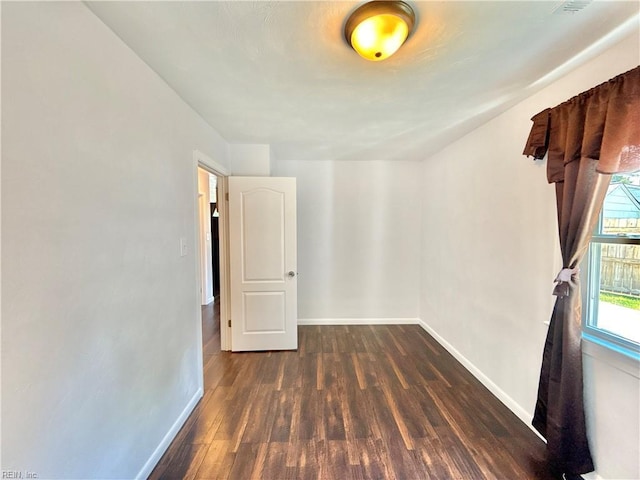 empty room featuring baseboards and dark wood-style flooring