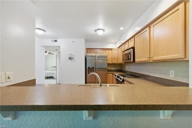 kitchen featuring a sink, stainless steel appliances, a peninsula, backsplash, and visible vents