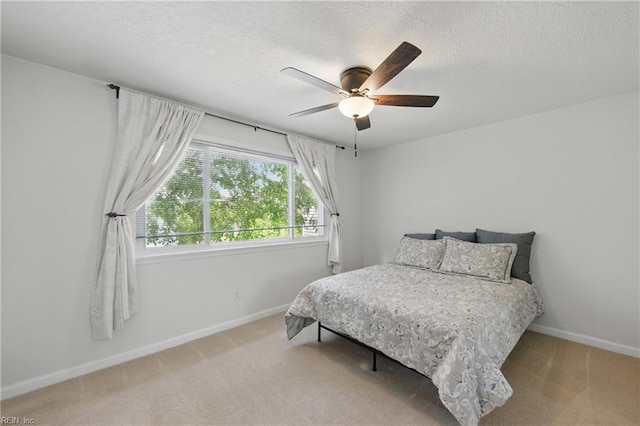 bedroom with baseboards, a ceiling fan, a textured ceiling, and light colored carpet