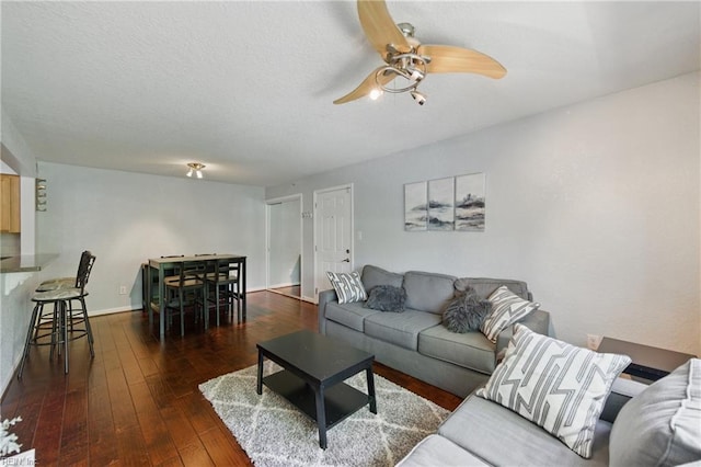 living area featuring baseboards, a ceiling fan, and hardwood / wood-style flooring