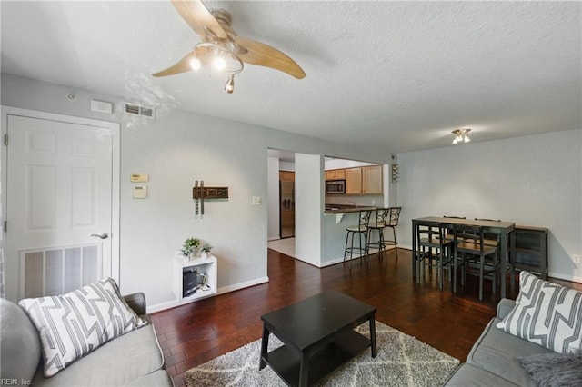 living room with visible vents, baseboards, ceiling fan, and wood finished floors