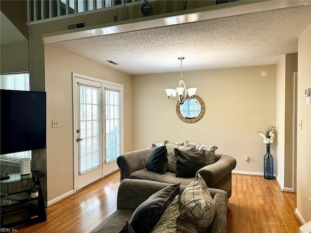 living area featuring baseboards, light wood-type flooring, and a notable chandelier